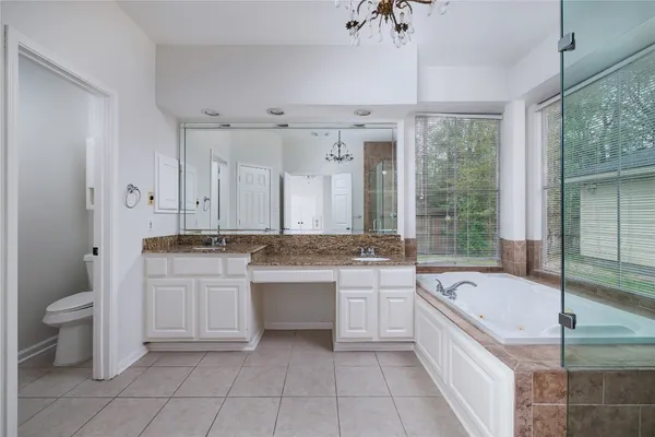 a large white bathroom with a granite countertop sink a toilet a mirror and bathtub