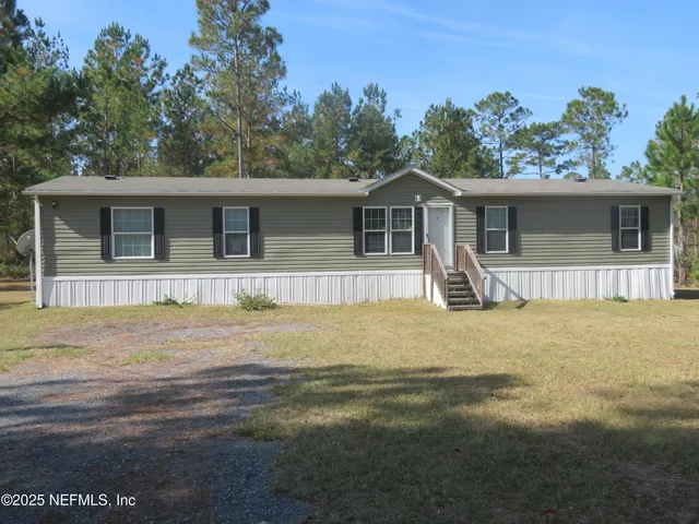 a front view of house with yard and trees in the background