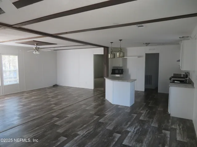 a view of a kitchen with refrigerator and wooden floor