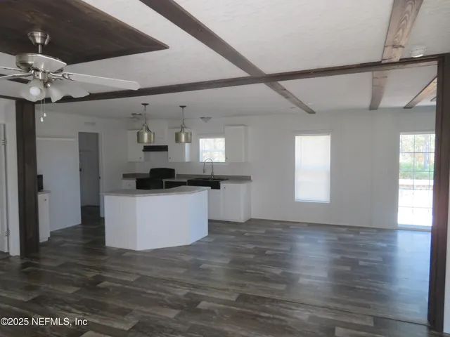 a kitchen view with wooden floor and white cabinets