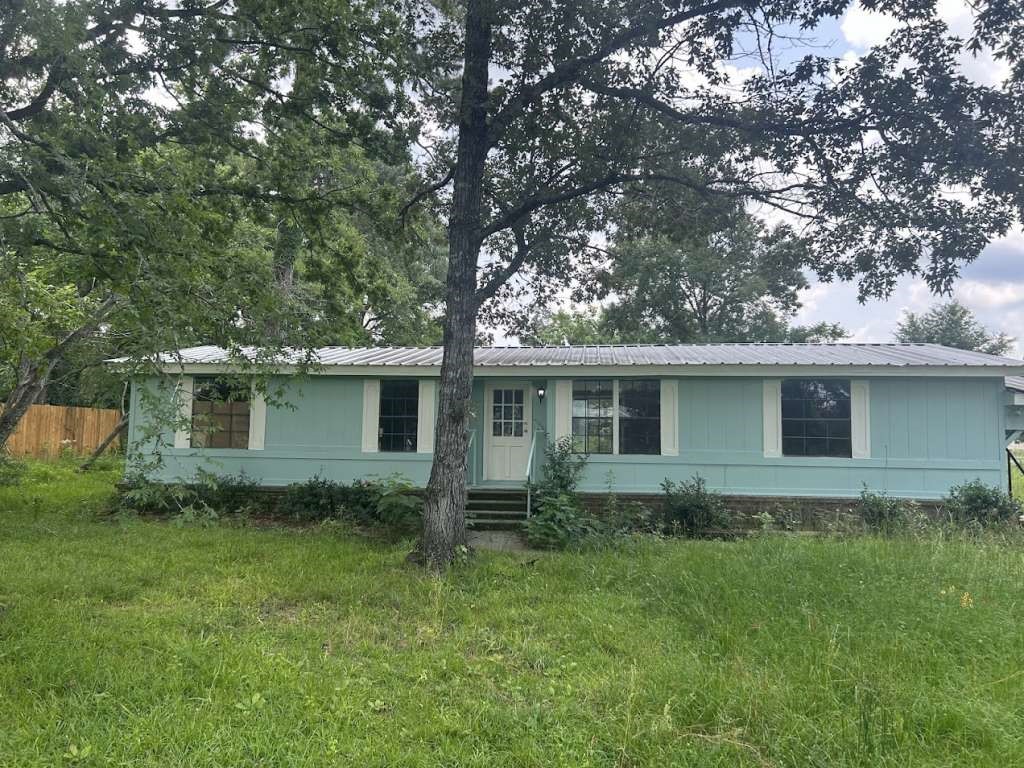 a backyard of a house with lawn chairs plants and large tree