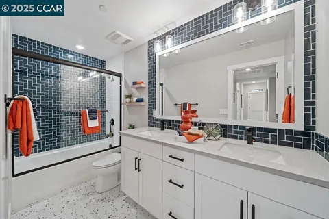 a bathroom with a double vanity sink toilet mirror and shower