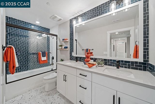 a bathroom with a double vanity sink toilet mirror and shower