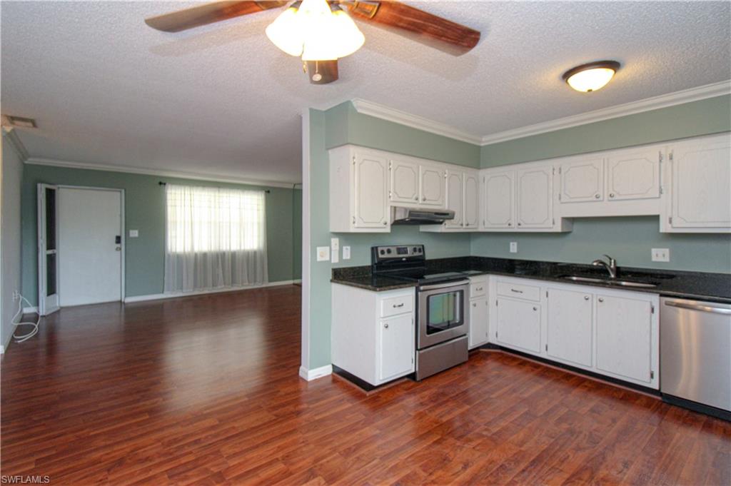 729 Palm View Drive, Unit D4 Naples, FL 34110 - Photo 11 of 23 a kitchen with granite countertop wooden floors stainless steel appliances and white cabinets