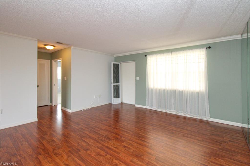 729 Palm View Drive, Unit D4 Naples, FL 34110 - Photo 9 of 23 a view of an empty room with wooden floor and a window