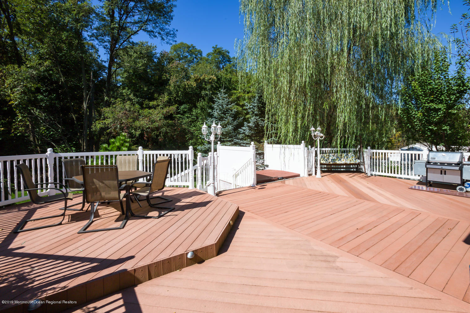 327 Wedgewood Road Morganville, NJ 07751 - Photo 28 of 33 a view of a patio with dining table and chairs with wooden floor and fence