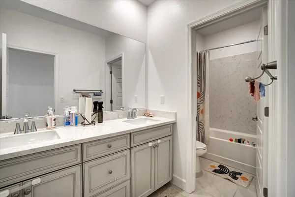 a bathroom with a double vanity sink toilet mirror and shower