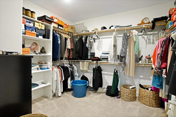 a view of walk in closet with clothes and shoes