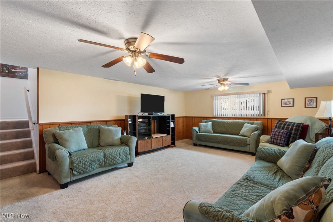 447 Center Road Bedford, OH 44146 - Photo 22 of 33 Carpeted living area featuring wooden walls, a wainscoted wall, stairway, and a textured ceiling