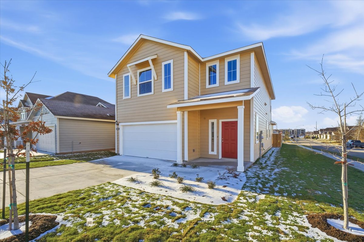 2601 Towy Road Pflugerville, TX 78660 - Photo 2 of 29 Charming two-story corner-lot home with a welcoming front porch, attached garage, and concrete driveway. Features warm neutral tones, a standout red front door with side window, and abundant natural light from multiple front-facing windows.