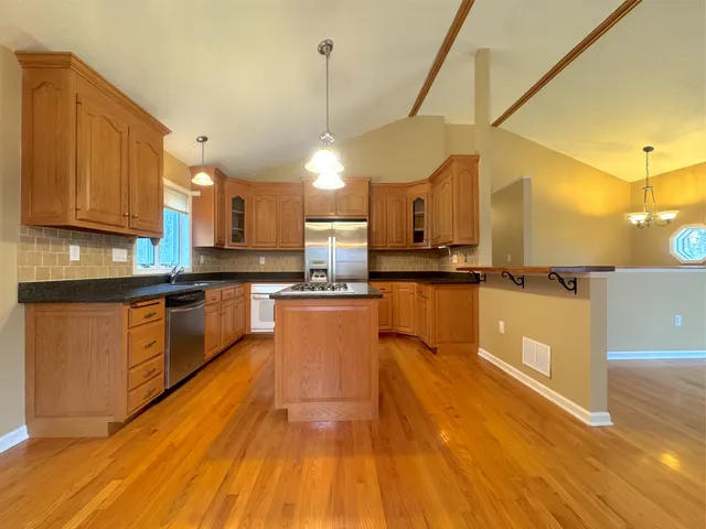 a large kitchen with stainless steel appliances and wooden cabinets