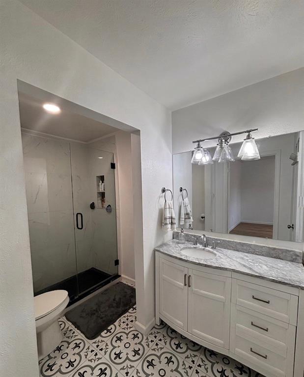 8057 Meadow Road, Unit 202 Dallas, TX 75231 - Photo 7 of 11 Full bathroom with vanity, a shower stall, and light tile patterned floors