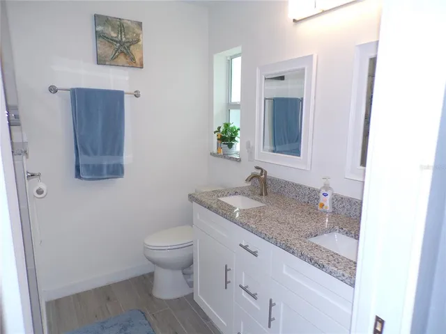 a bathroom with a granite countertop toilet sink and mirror