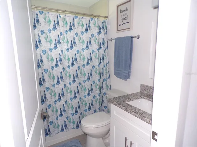 a bathroom with a granite countertop sink toilet and shower