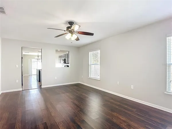 a view of an empty room with a window and wooden floor