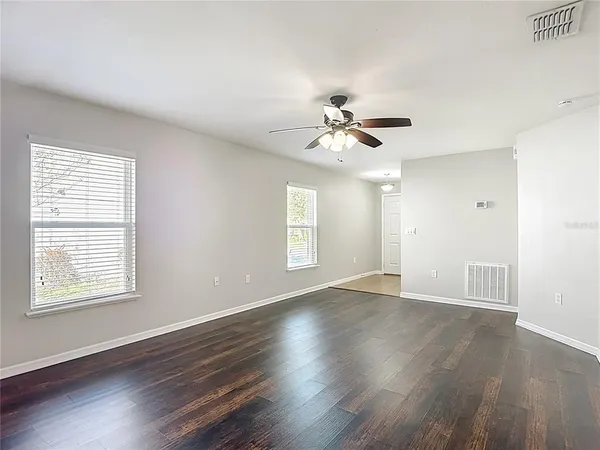 an empty room with wooden floor and windows