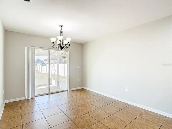 an empty room with wooden floor chandelier fan and windows