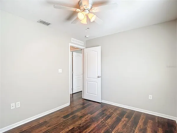 a view of empty room with wooden floor and fan