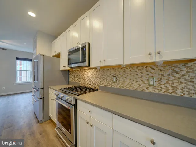an empty room with wooden floor ceiling fan and windows