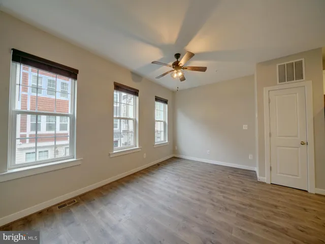 an empty room with wooden floor and windows