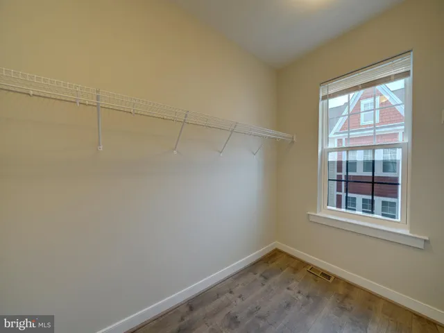 an empty room with wooden floor chandelier fan and windows