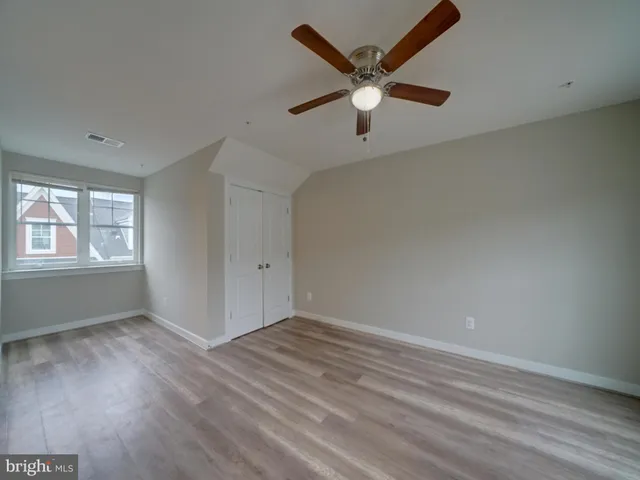 an empty room with a window and ceiling fan