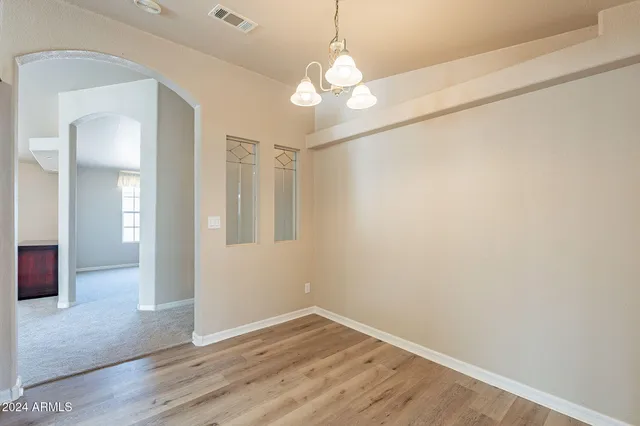 an empty room with chandelier fan and windows