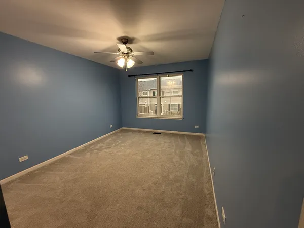 a view of an empty room with a chandelier fan