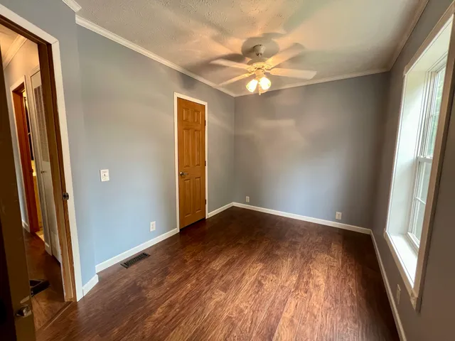 an empty room with wooden floor and windows
