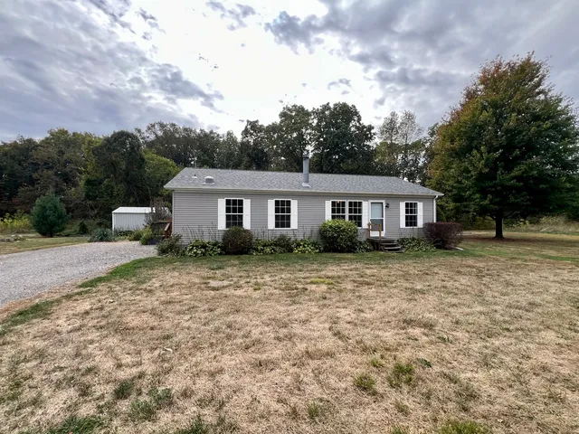 a front view of house with yard and trees around