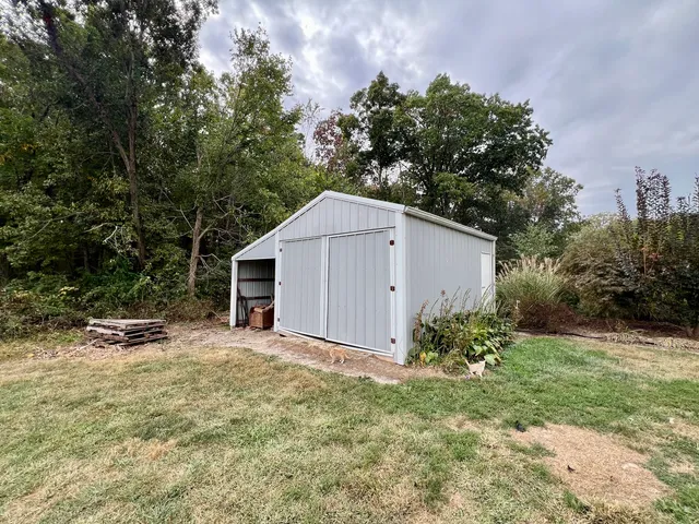 a view of a barn in the yard with large trees