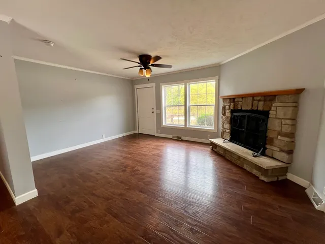a view of wooden floor fire place and windows in an empty room