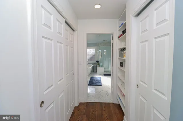 a view of a hallway with a hardwood floor and a bathroom