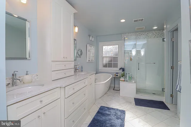 a bathroom with a double vanity sink a toilet a bathtub and shower