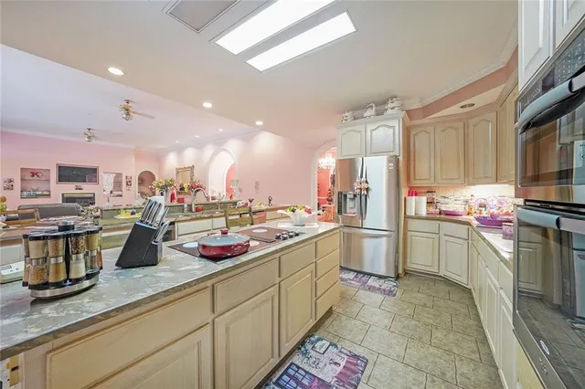 a room with stainless steel appliances kitchen island granite countertop a sink and cabinets