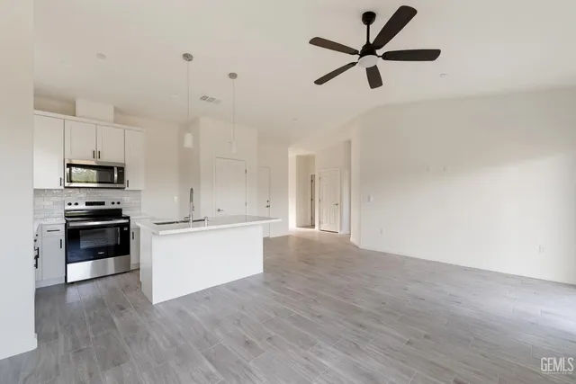 a kitchen with granite countertop a stove a sink and a refrigerator