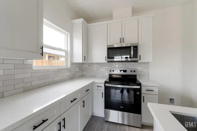 a kitchen with cabinets appliances a sink and a window