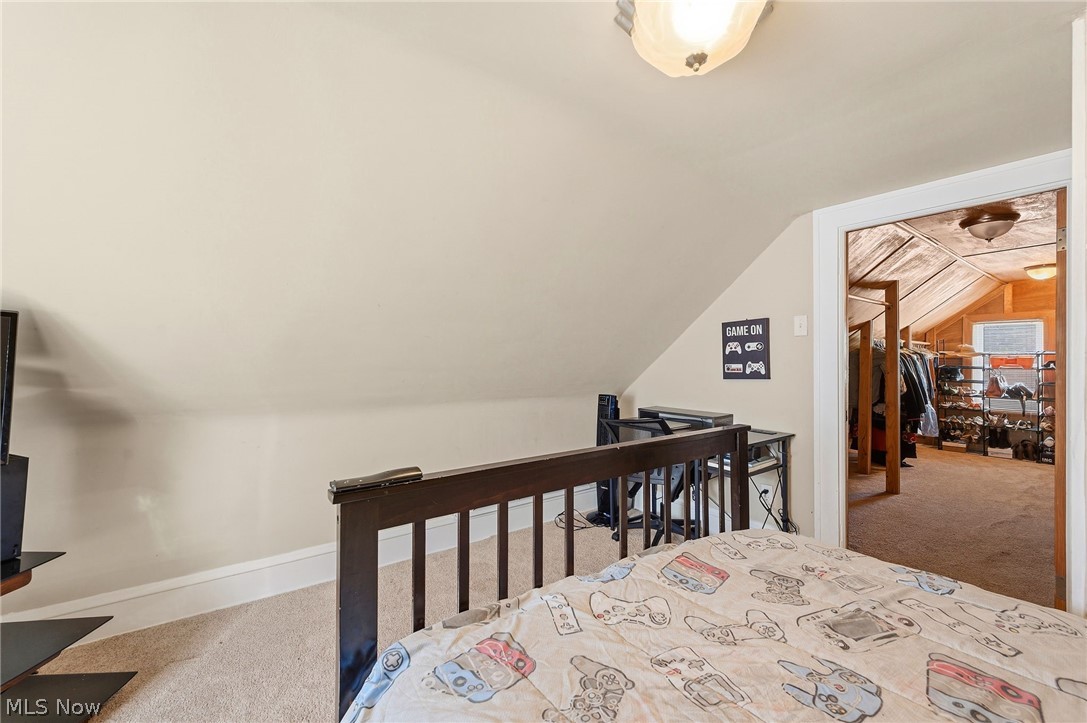 3386 Sylvanhurst Road Cleveland Heights, OH 44112 - Photo 34 of 46 Carpeted room featuring a sloped ceiling and an open doorway leading to an additional space with wood-finish paneling