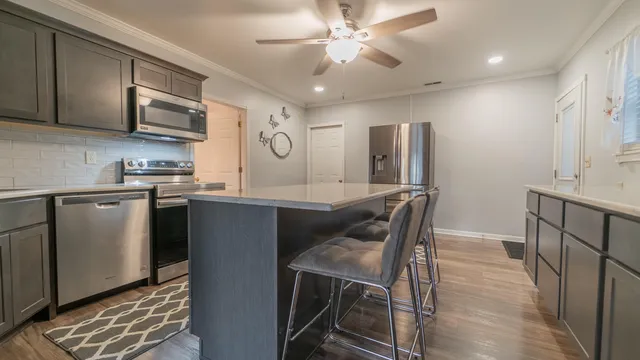 a kitchen with stainless steel appliances granite countertop a sink a stove a refrigerator with grey cabinets