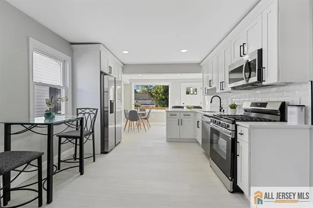 a kitchen with stainless steel appliances granite countertop a stove top oven a sink dishwasher a dining table and chairs with wooden floor