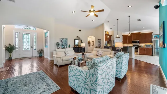 a living room with furniture kitchen view and a wooden floor