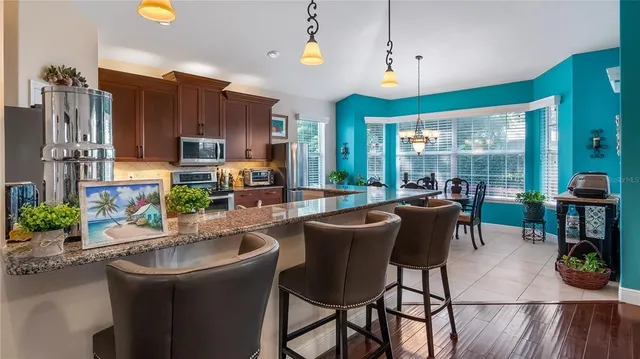 a kitchen with kitchen island granite countertop a table chairs microwave and cabinets