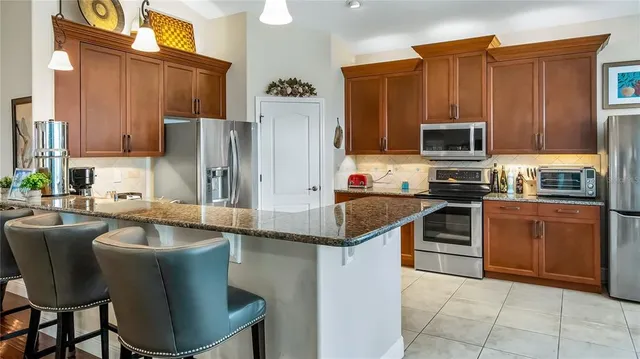 a kitchen with stainless steel appliances granite countertop a stove refrigerator sink and microwave
