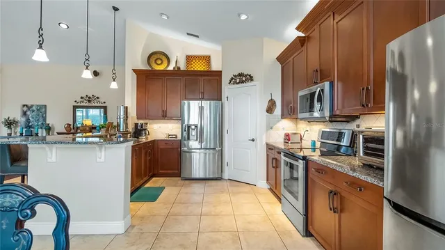 a kitchen with stainless steel appliances granite countertop a refrigerator and a stove top oven