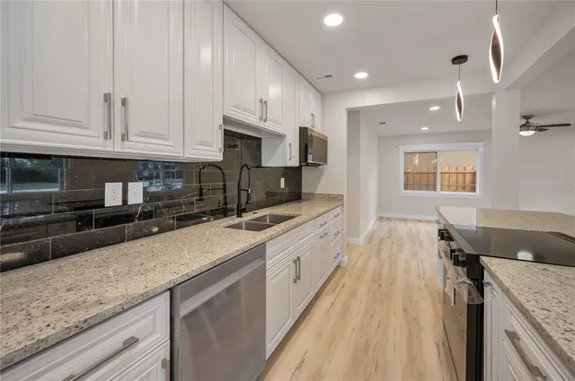 a large kitchen with stainless steel appliances granite countertop a lot of counter space and wooden floors