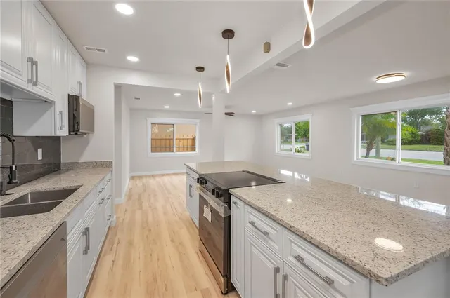 a kitchen with stainless steel appliances granite countertop a sink a stove and a wooden cabinets
