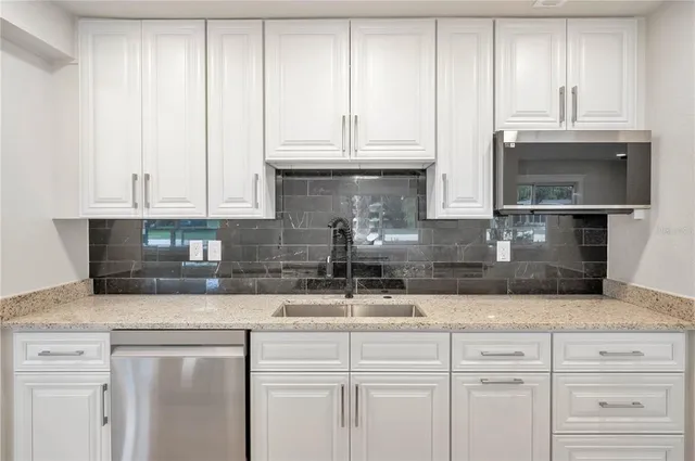 a kitchen with granite countertop white cabinets and a stainless steel appliances