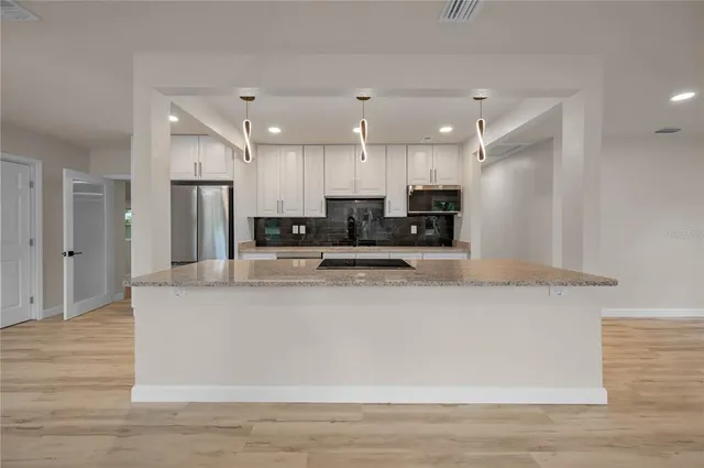a large kitchen with stainless steel appliances kitchen island a large counter top and wooden floors