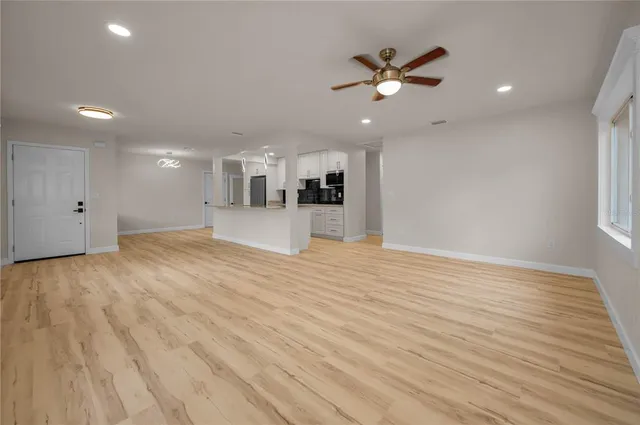 a view of an empty room with wooden floor and a ceiling fan