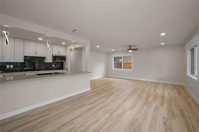 a view of kitchen with kitchen island granite countertop a stove top oven a sink and a counter space